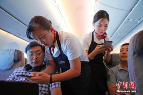 資料圖：乘務(wù)員們在客艙內(nèi)為旅客調(diào)試機上上網(wǎng)功能。<a target='_blank' ><p  align=