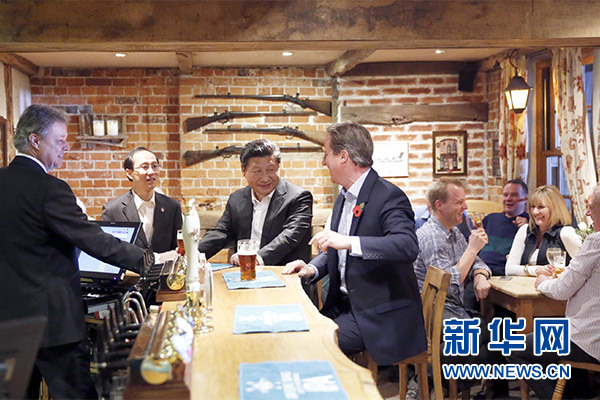 這是會晤結(jié)束后，習近平在卡梅倫陪同下乘車前往當?shù)匦℃?zhèn)體驗酒吧文化。新華社記者 鞠鵬 攝